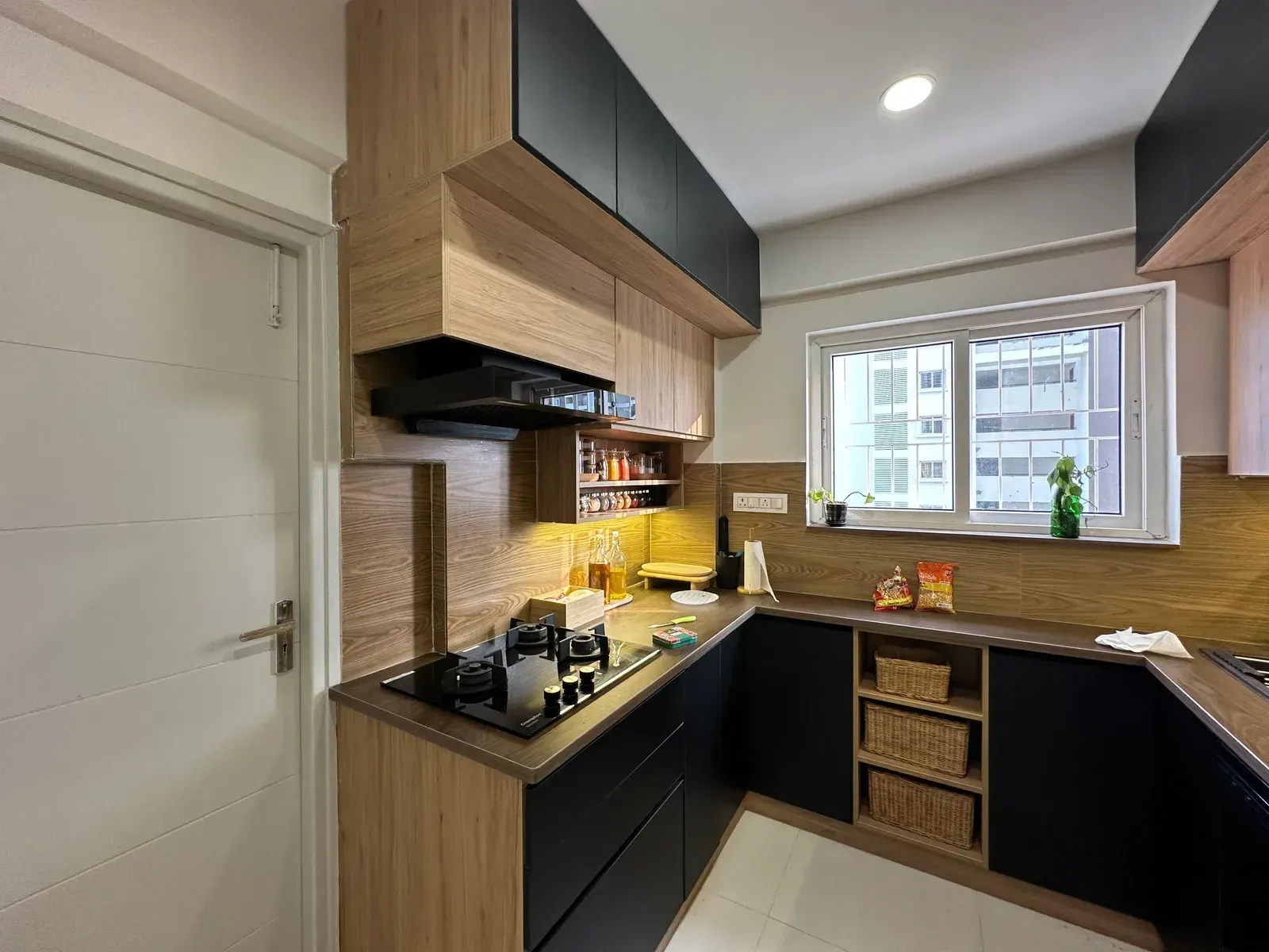 U-shaped kitchen with black base cabinets and oak wall units — The Aakar